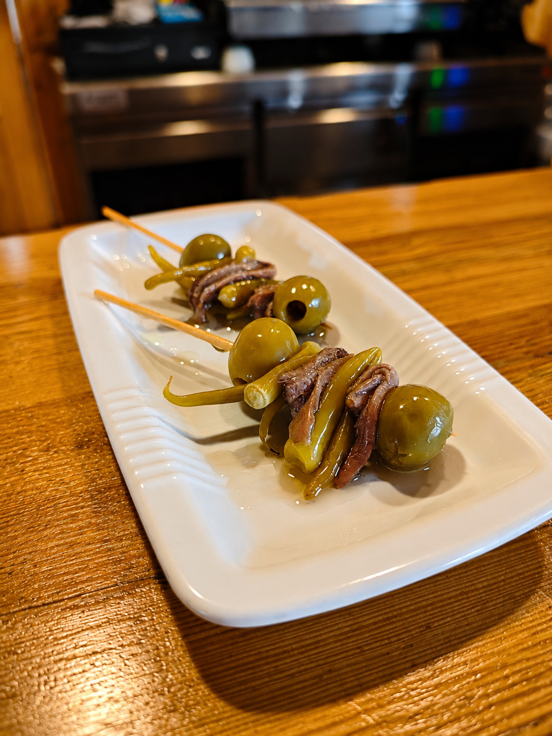 Gildas de anchoa, aceituna y guindilla en plato blanco