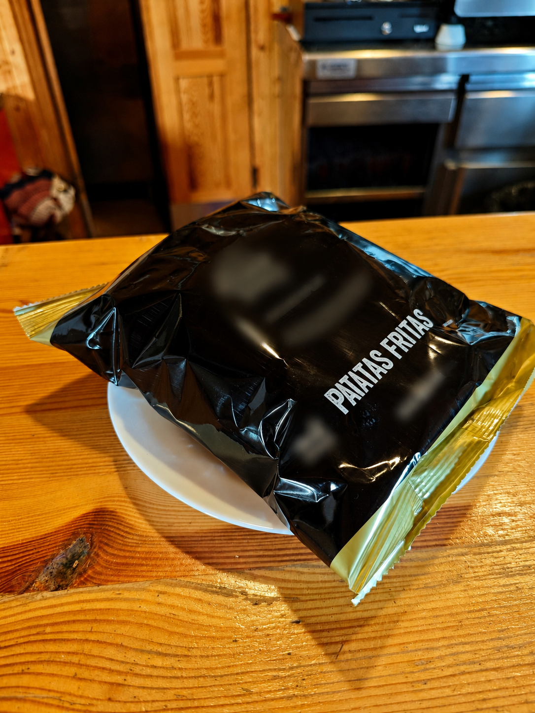 Bolsa de patatas fritas en un platito sobre la barra de madera